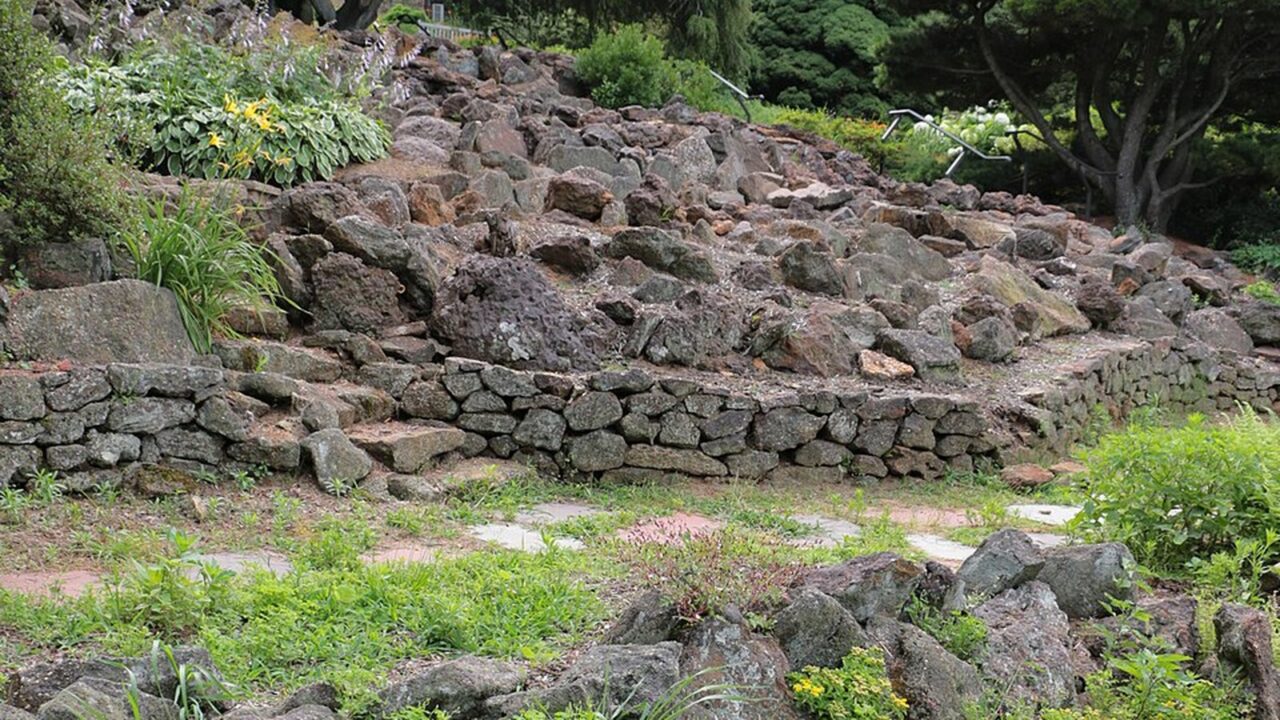 Rocaille en pierres naturelles et muret de pierres sèches dans un jardin en pente